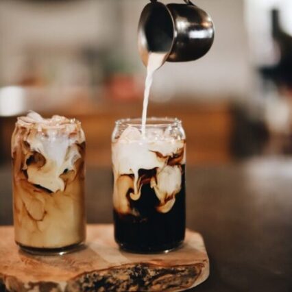 milk pouring into iced coffees on wooden shelf, the difference between iced coffee and cold brew