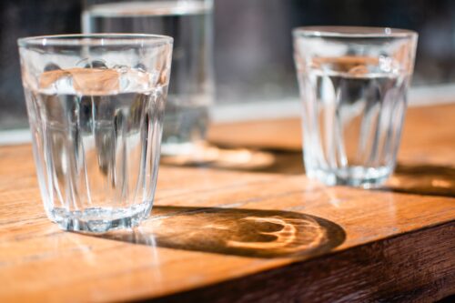 7 Fail-Proof Tips For Making Cold Brew Coffee At Home 2 three glasses of water on a wooden bar in the sunlight, using filtered water for coffee, filtered water