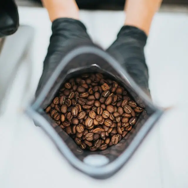 Dark Roast vs. Light Roast: 5 Mind-Blowing Differences 11 hand wearing black gloves holding open bag of roasted coffee beans with beans in focus, how to properly store coffee beans
how to store coffee beans properly