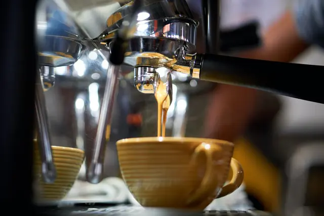 Dark Roast vs. Light Roast: 5 Mind-Blowing Differences 9 espresso brewing from double spouted portafilter into yellow striped cup,