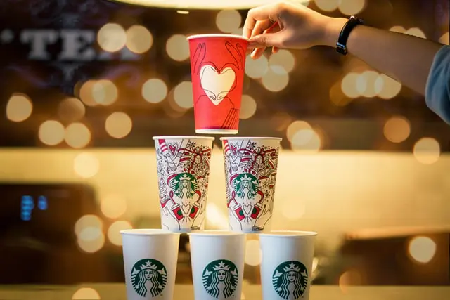 pyramid of starbucks winter cups with golden lights in blurred background