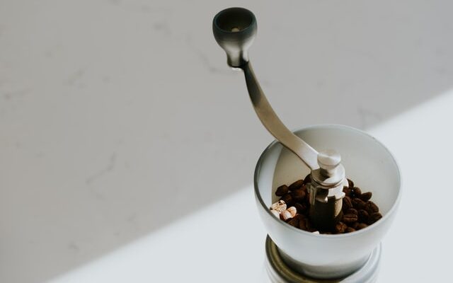 beans in hopper of hario manual coffee grinder in sun, best manual coffee grinders