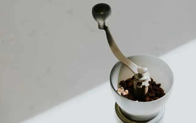 The 5 Best Manual Coffee Grinders In 2026: Brew Better Coffee 1 beans in hopper of hario manual coffee grinder in sun, best manual coffee grinders