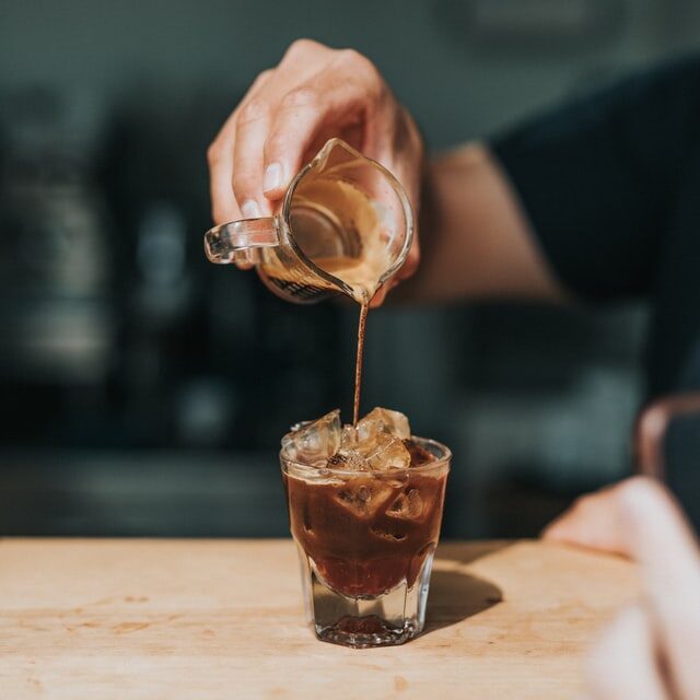 pouring espresso into glass with ice on wood table, Macchiato iced