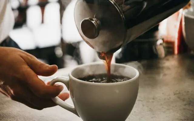 How To Use French Press Coffee Makers + The #1 Mistake 1 pouring coffee from French press into white mug, how to use french press coffee makers