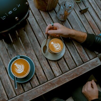 latte and cappuccino on outdoor wooden table beside motorcycle helmet, latte vs cappuccino