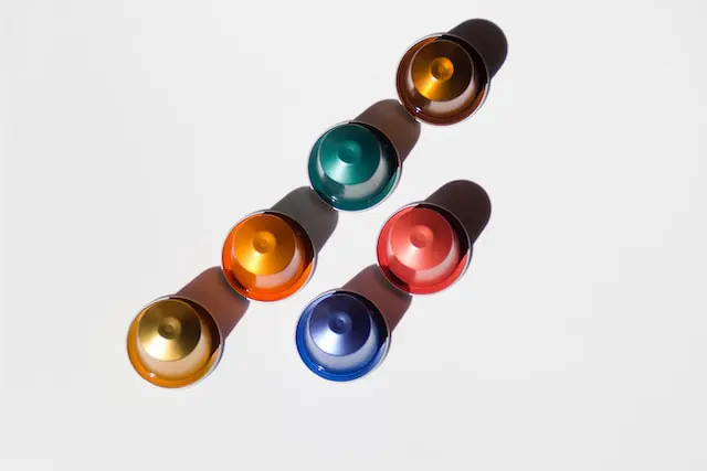 six colorful Nespresso pods on white surface with shadows