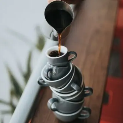 Coffee pouring into a stack of espresso cups