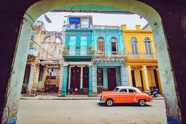 orange vintage car on Cuban street with bright buildings