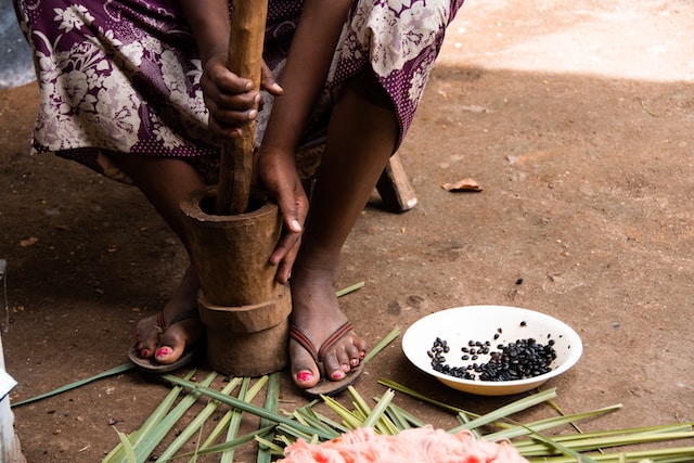 woman grinding coffee beans in mortar and pestle 