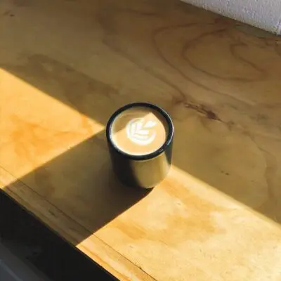cortado coffee in black stemless cup in the sun