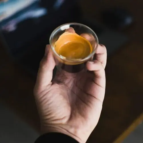 How Much Caffeine is in a Shot of Espresso? +5 Proven Facts 10 espresso shot in shot glass in man's hand